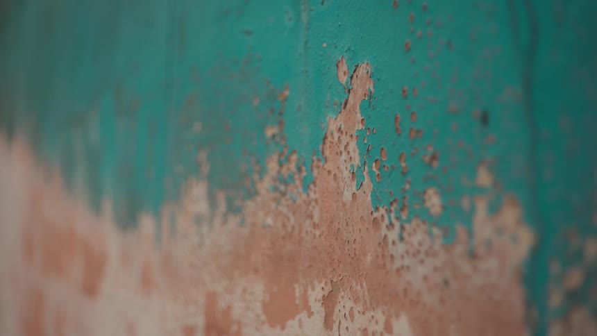 Aquamarine colored paint peels from a wall