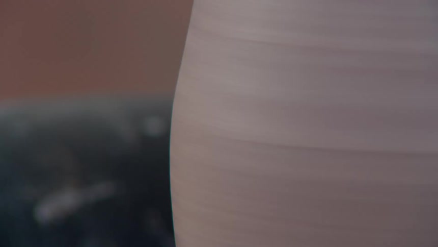 A hand shaping a clay vase over a turning table