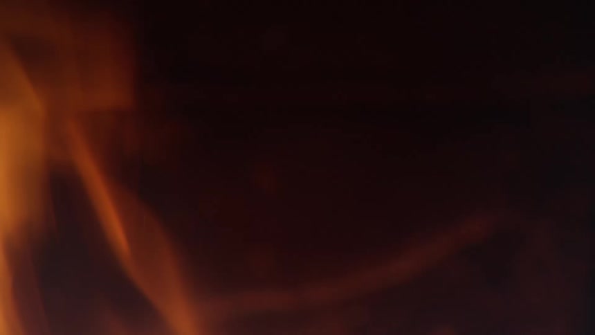 A closeup of flames dancing in a dark smoke filled space