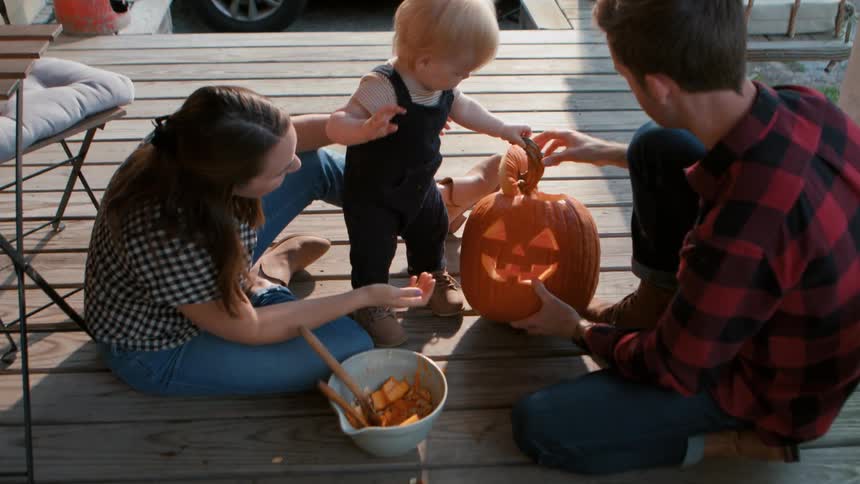 A family carving a jack o lantern on the porch at dusk