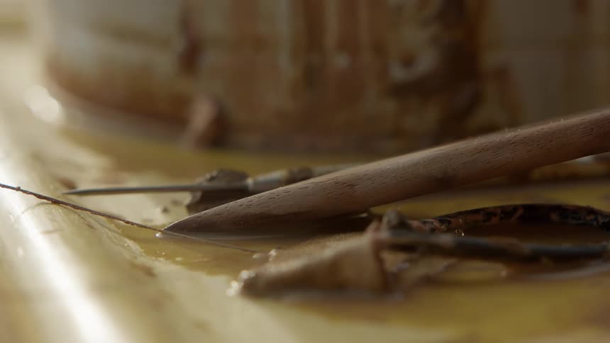 Thin piece of wood in water next to a bucket