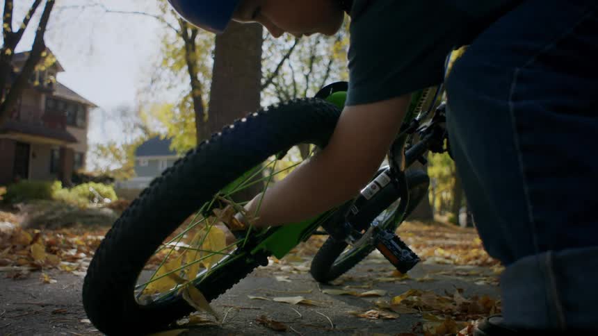 A child lifts up his bicycle