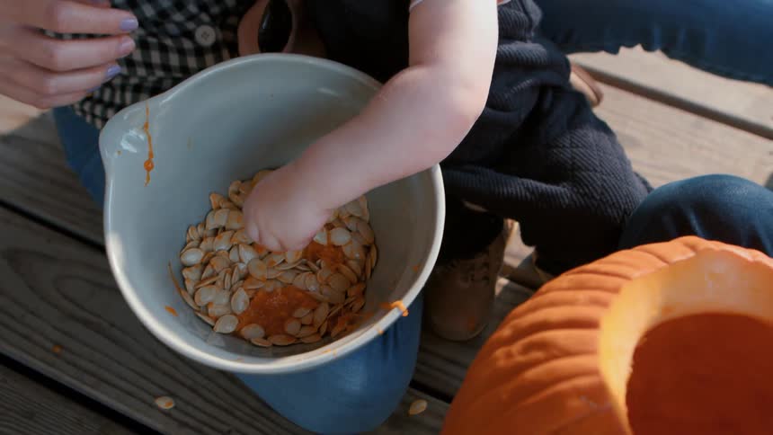 A family carving a jack o lantern on the porch at dusk