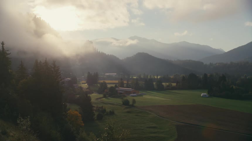 Landscape of a farm surrounded by trees and mountains in the background