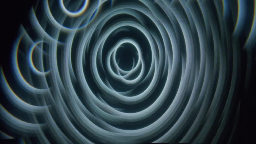 A swirling pattern of concentric circles with a dark center and a faint glow around the edges
