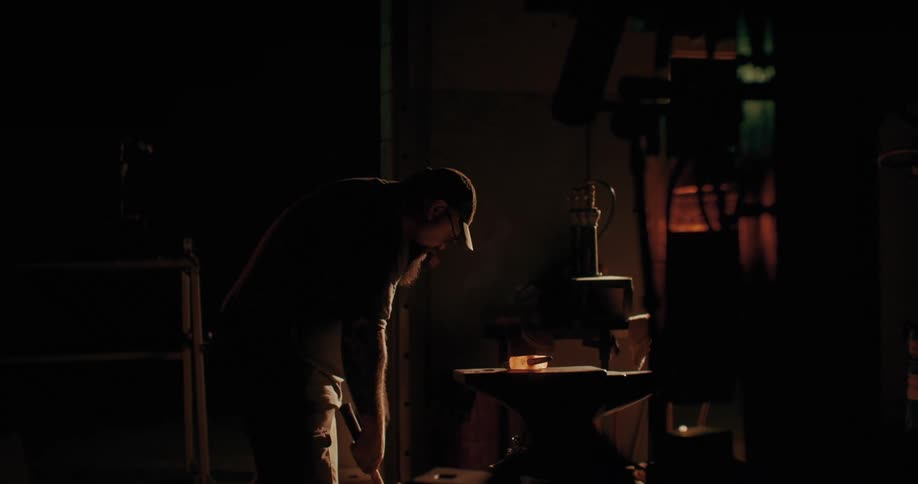 A blacksmith hammers a piece of redhot metal on an anvil