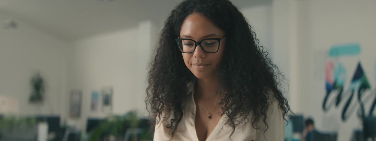A happy woman with curly hair stretches and prepares to work in the office
