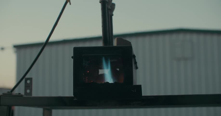 A blacksmith lights a small furnace at morning
