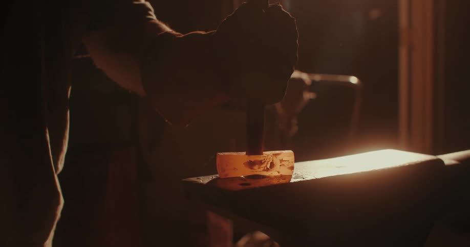 Blacksmith man placing a wooden handle on a hot plate of a hammer