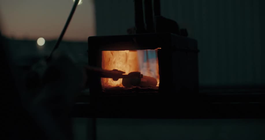 Silhouette of a person with a tool moving metals inside a blowtorch