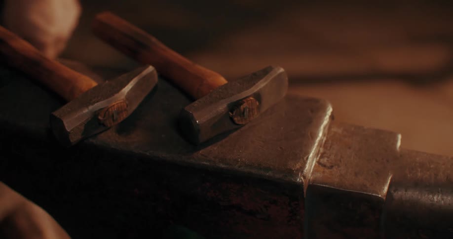 A blacksmith places a couple of hammers over an anvil
