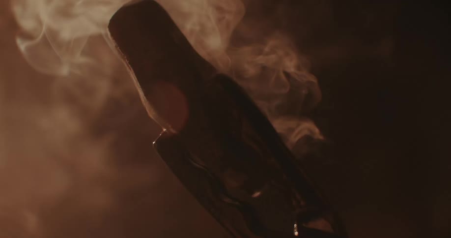 Close up of a pair of tongs holding a smoking hot piece of metal