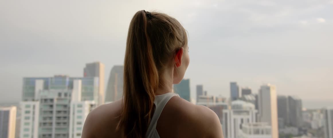 A woman admires the city skyline from a window at morning