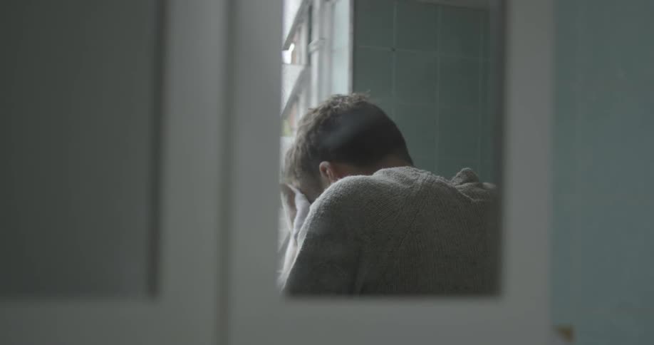 A man cleans his face with a white towel