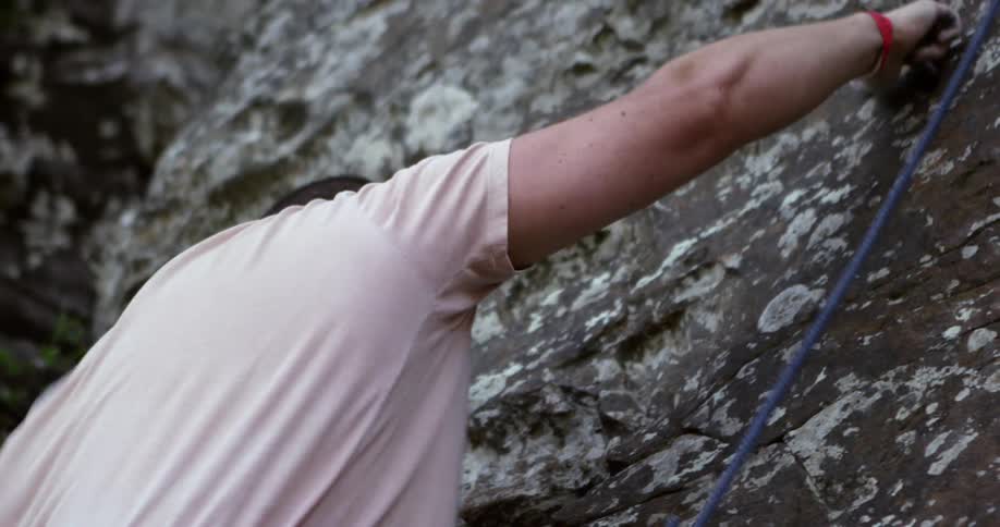 Rock climber reaching out to pull himself further up the rock
