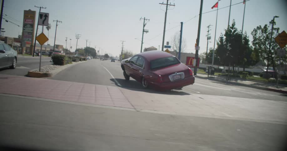 A lowrider car performs a wheelie on a city street