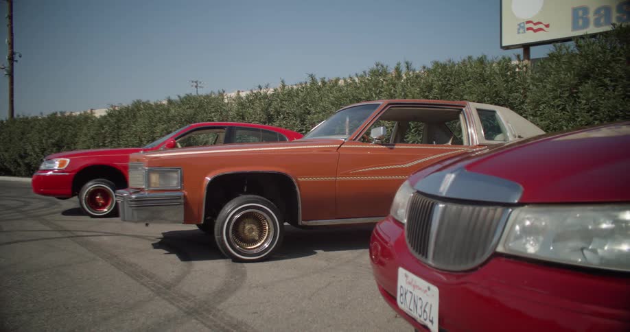 Three lowrider cars parked in a parking lot
