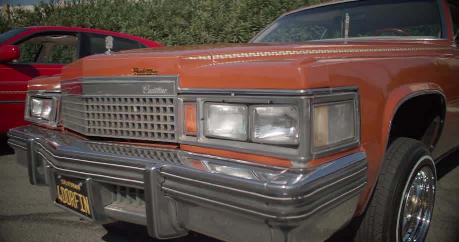 Two lowrider cars parked in a parking lot