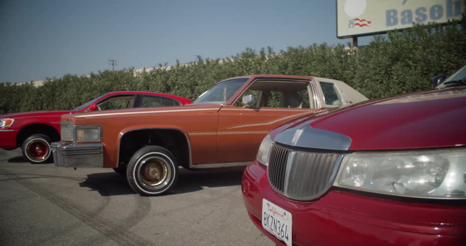 Three lowrider cars parked in a parking lot