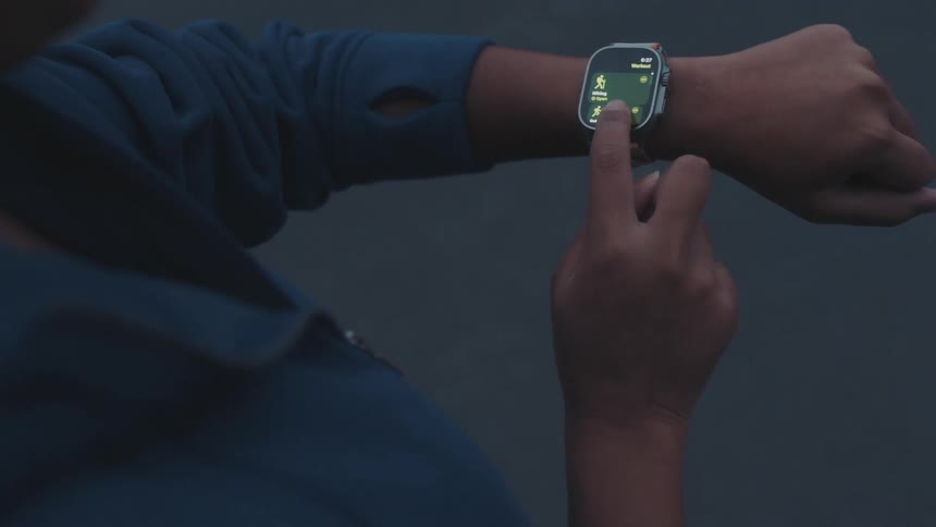 A person wearing a blue jacket starts a workout on their smartwatch