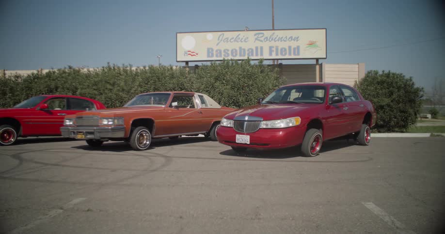 Cars are parked in the lot outside the baseball field