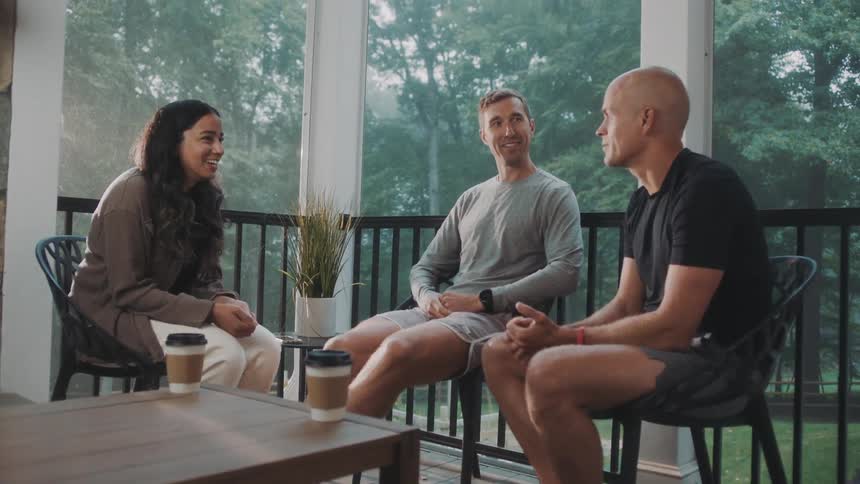 Two men and a woman sitting on a chair and talking to each other
