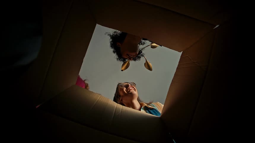 A group of happy friends opens a cardboard box to unpack it