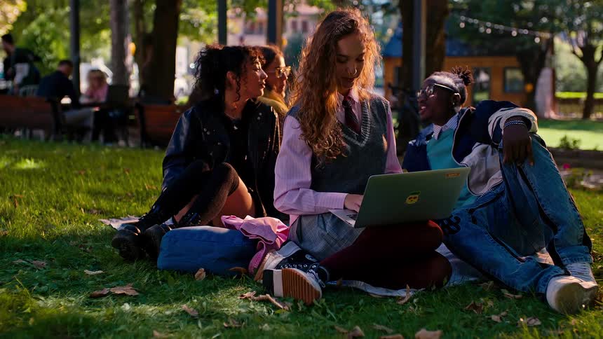 Group of college students sitting on the grass chatting among themselves in a cheerful manner