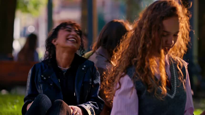 Group of friends and students sitting on the grass chatting happily