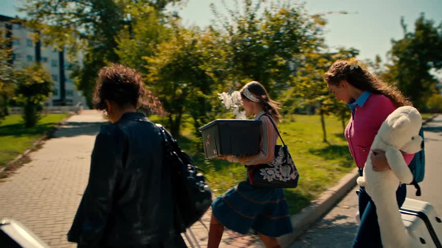 A group of happy friends arrives at a university campus carrying personal belongings