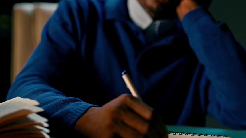 Student sitting in a library writing in notebook