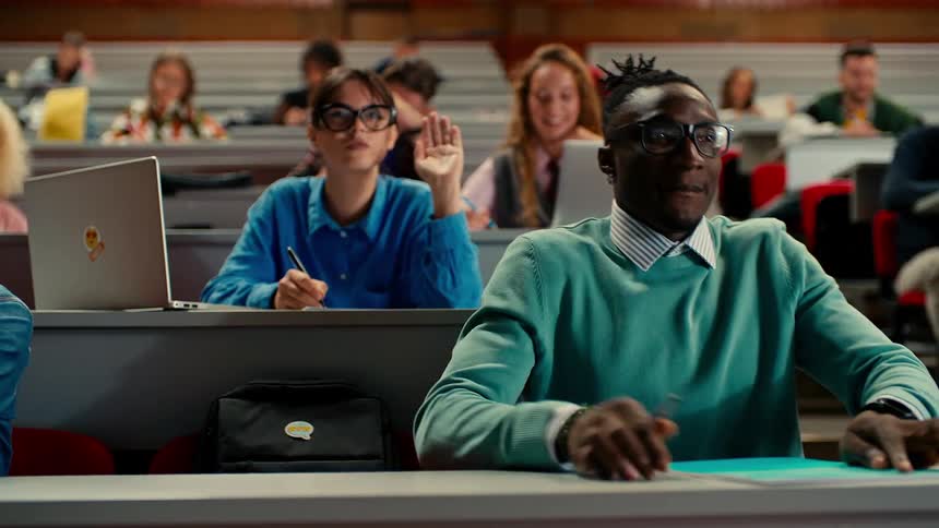 Students in an auditorium raising their hands