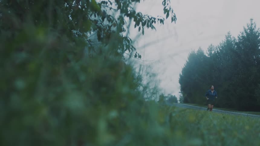 Woman running on a road with trees and foliage