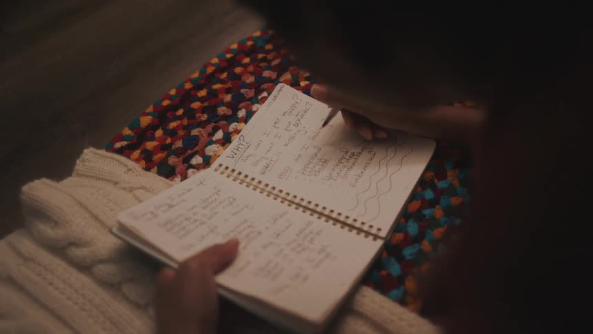Woman writing in a notebook on a rug
