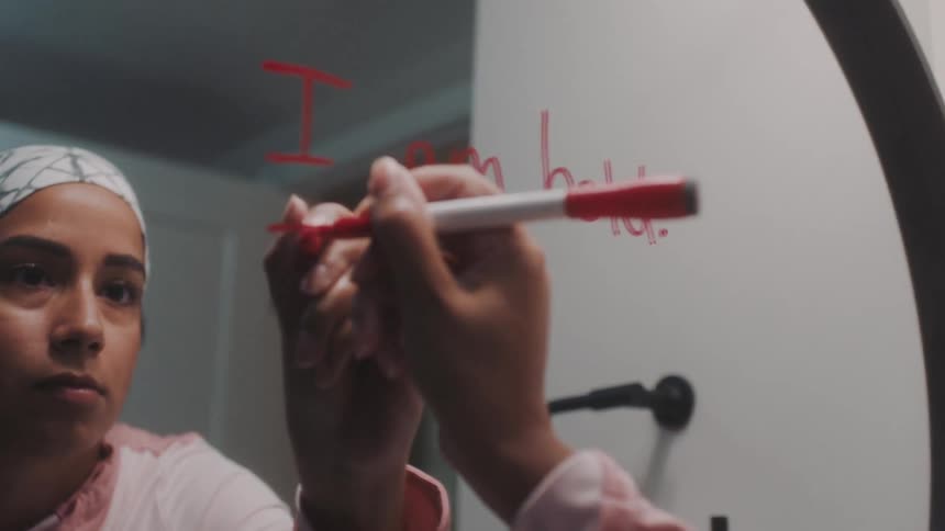 Woman with a red pen writing on the bathroom mirror