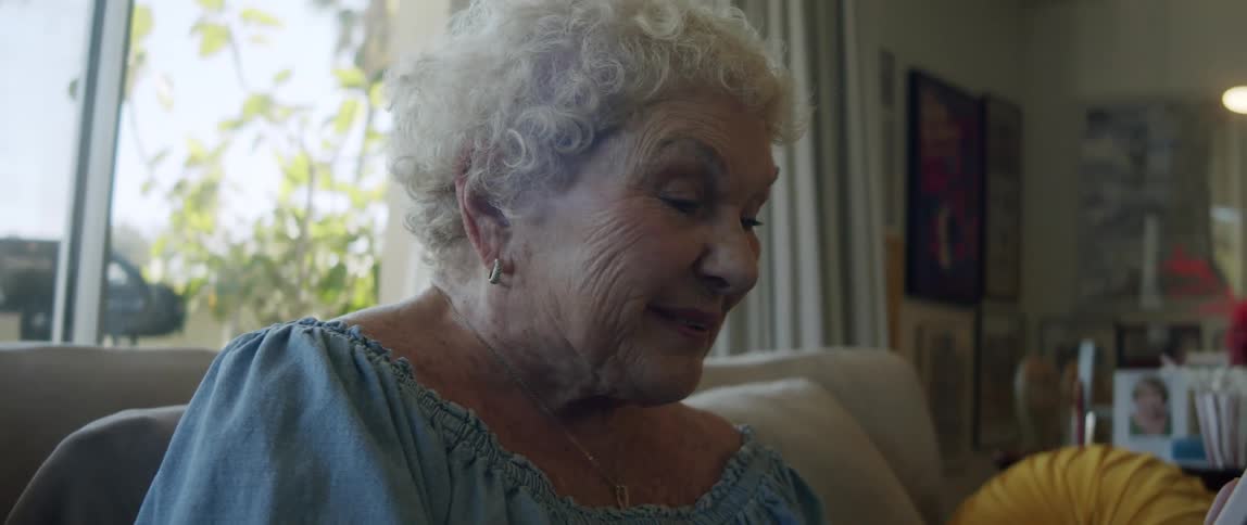 Elderly lady sitting in living room talking on her smartphone