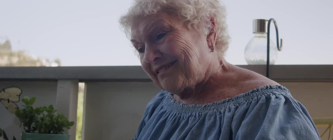 Happy elderly lady sitting reading newspaper