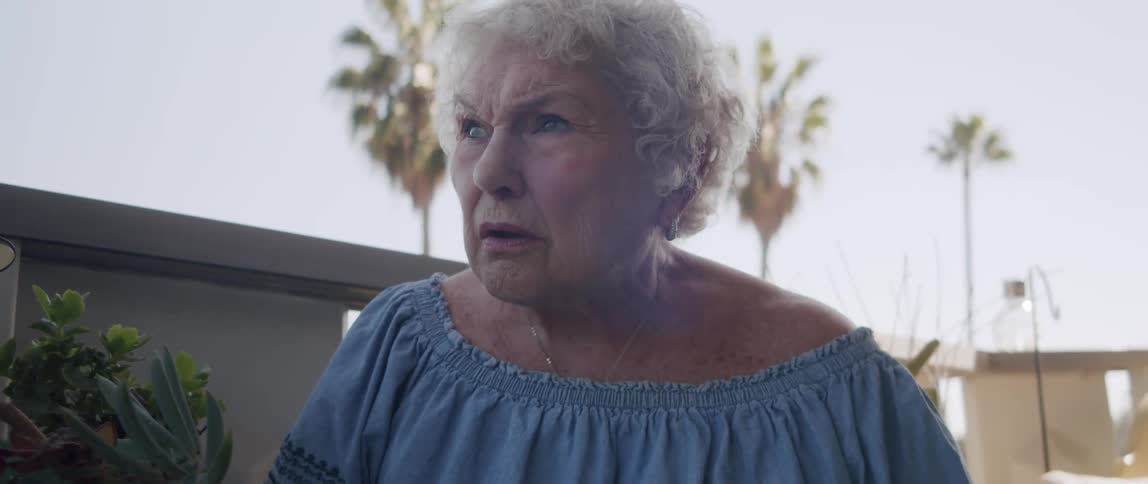 Elderly lady looking in disbelief while reading a newspaper