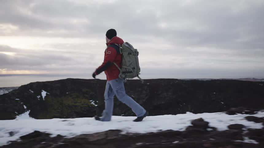 Man with backpack walking on snowy mountain peak