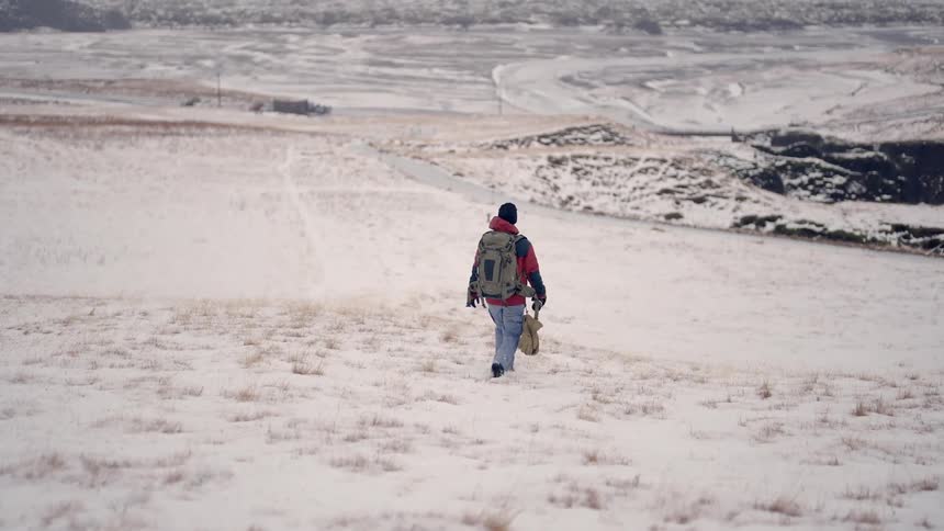 A man with a backpack hikes through a snowy landscape