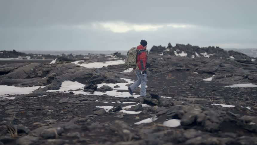 Man with backpack and professional camera walking through snowy natural environment