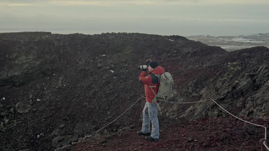 A photographer takes pictures of a barren mountain range