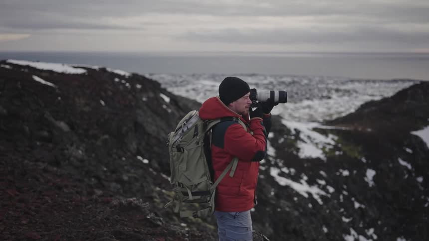 Photographer on a high mountain using a professional camera with zoom lens