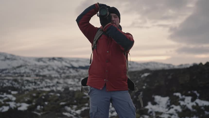 Photographer using a professional camera with zoom lens in a snowy mountain environment