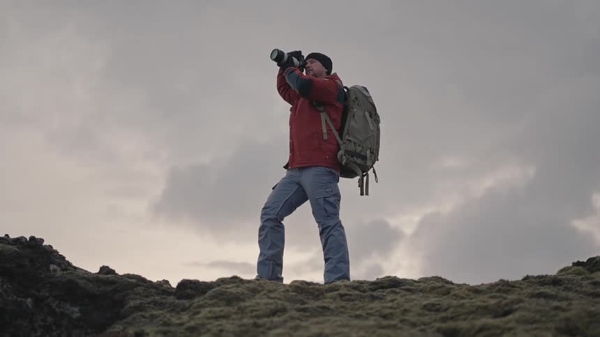 A photographer takes pictures of a barren snow covered mountain range