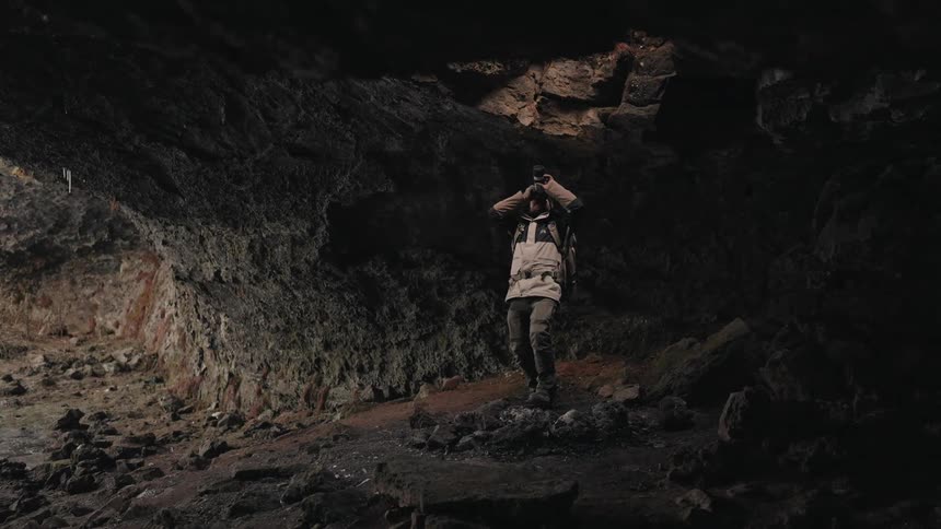 Man inside a cave using a camera pointing upwards