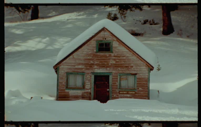 Vintage footage of a small cabin in the wood surrounded by snow