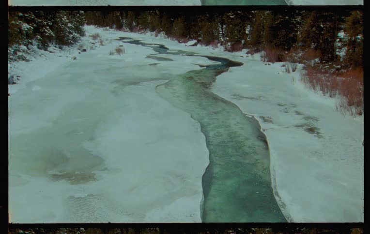 A winding river flows through a snowy landscape captured on vintage film
