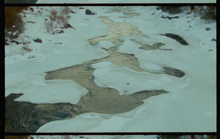 Water flows down a river in winter
