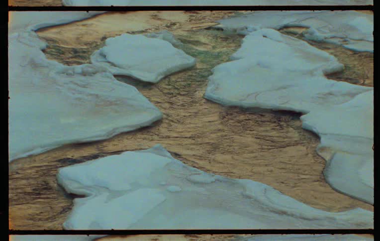 A river flows through a field of melting ice captured on vintage film